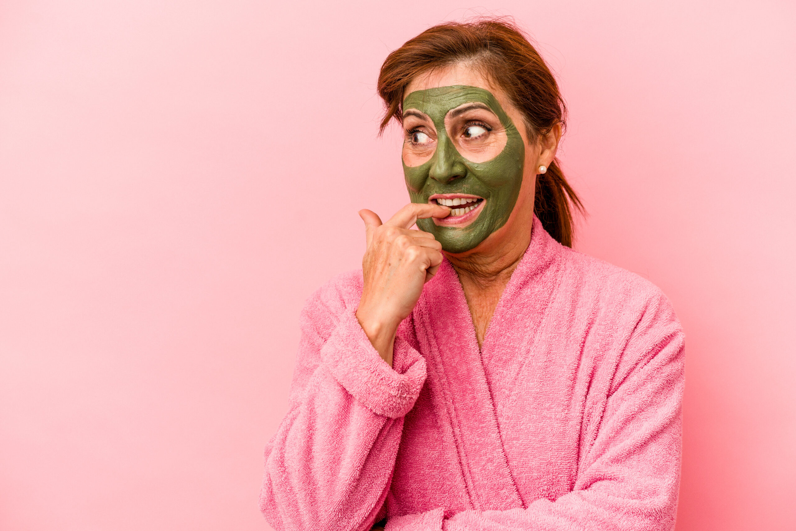 žena s pleťovou maskou na obličejí na růžovém pozadí