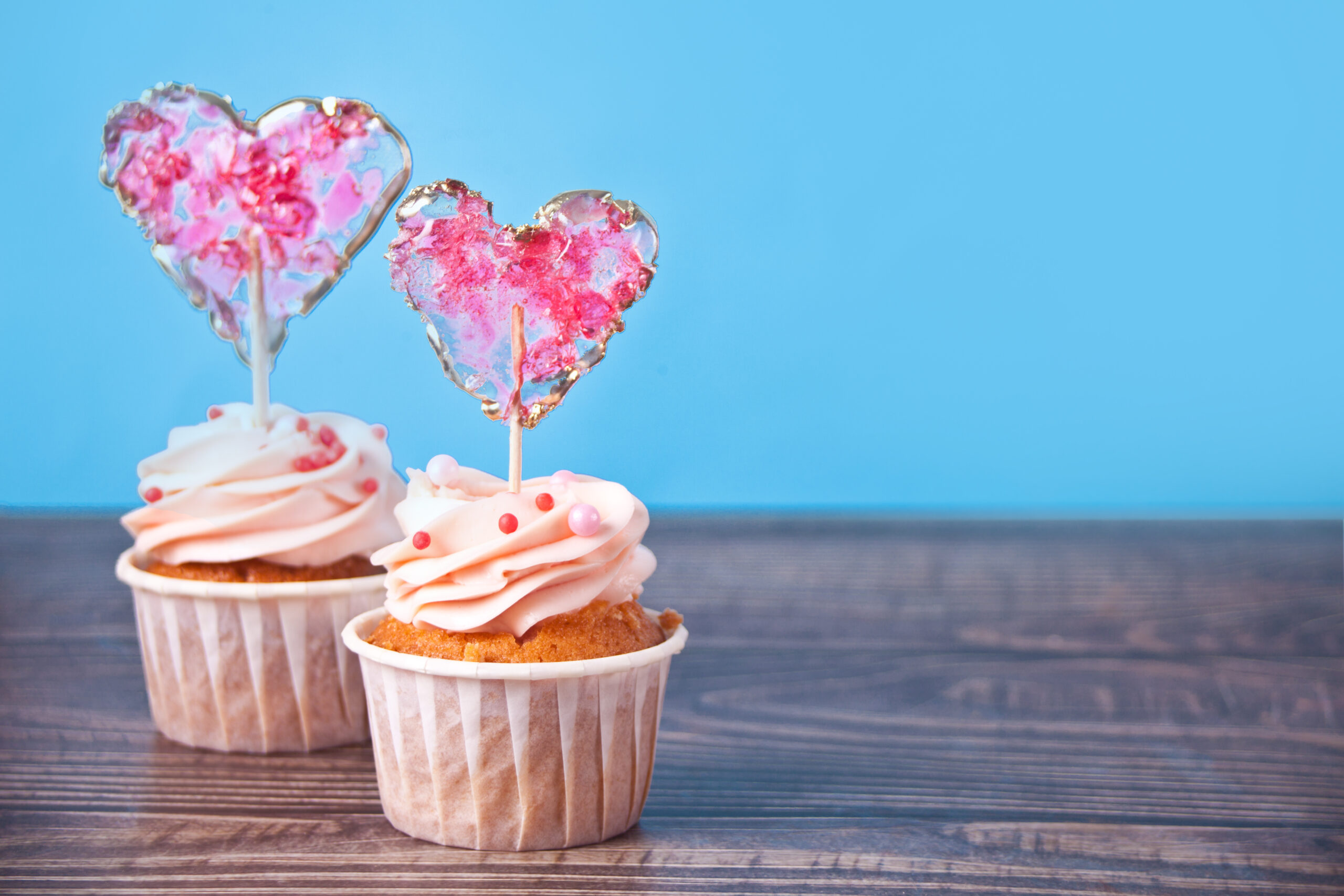 dva cupcakes s růžovými srdíčky na modrém pozadí