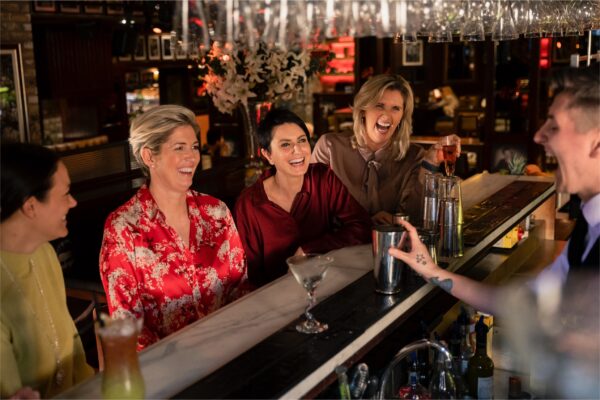 Skupina žen sedící u baru a baví se při skleničce drinku
