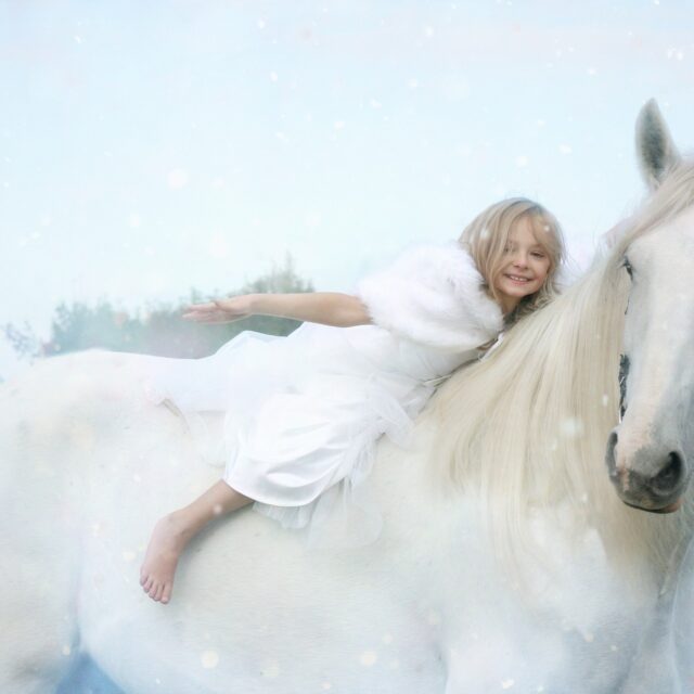 malá holka na bílém koni a padající sníh